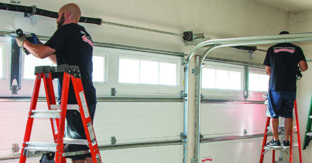 Technicians repairing white garage door springs.