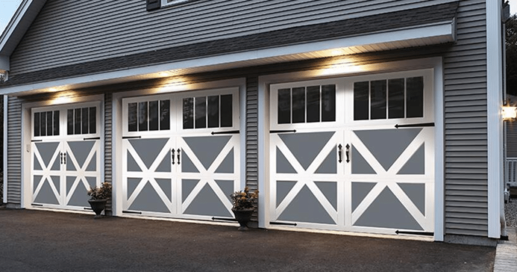 Three white barn-style garage doors lit up.