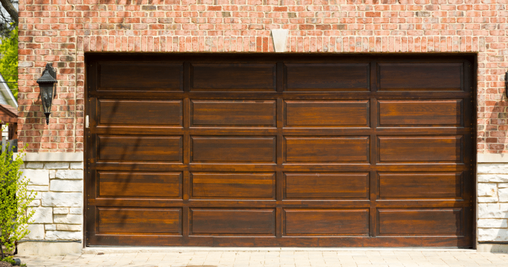 Brown wooden garage door on brick house.